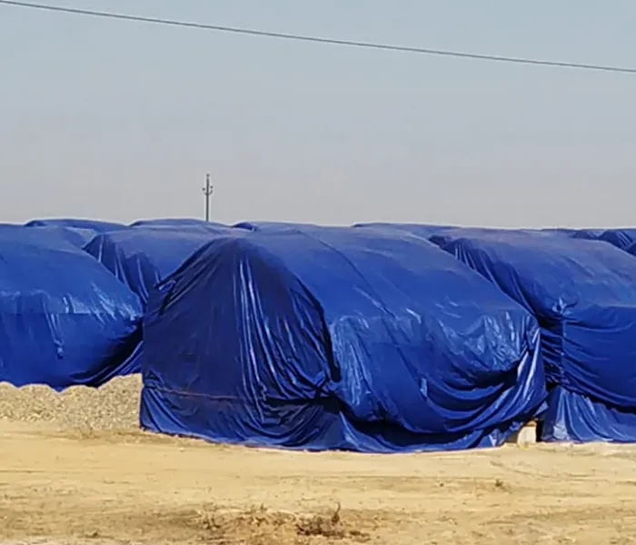 Blue multilayer tarpaulin covering a large outdoor stack