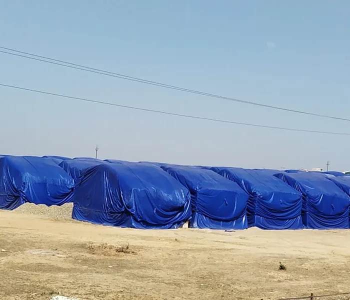 Row of blue tarpaulin covers protecting stacked goods outdoors